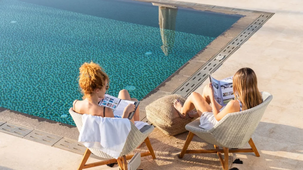 Détente au bord de la piscine de la Divine Villa à Akrotiri, Crète, avec deux personnes lisant près de l’eau.