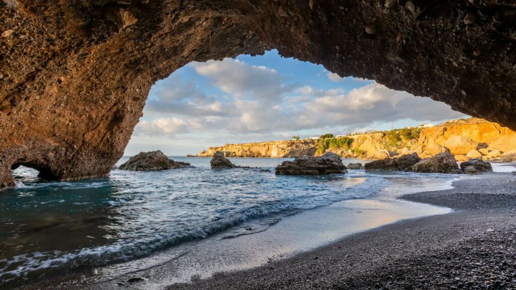 Vue depuis l'intérieur d'une grotte marine avec la mer et le littoral rocheux de Chania en arrière-plan