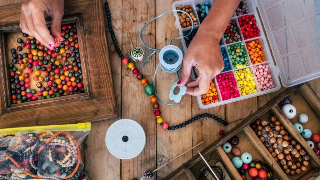 Artisan crétois fabriquant des bijoux colorés avec des perles et du fil dans un atelier traditionnel