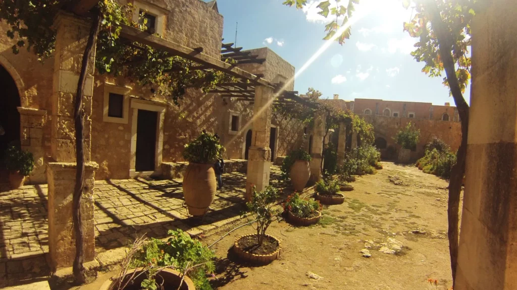 Cour traditionnelle dans un village crétois avec des vignes et des jarres en terre cuite, baignée de soleil