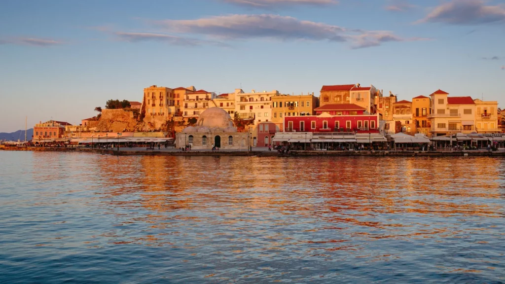 Vue du port vénitien de Chania au coucher du soleil avec des bâtiments historiques en arrière-plan